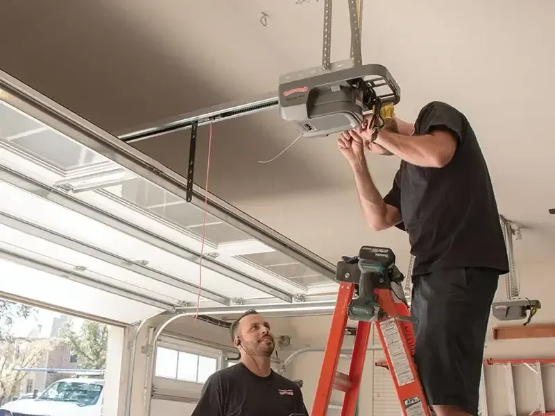 Two technicians installing a garage door opener